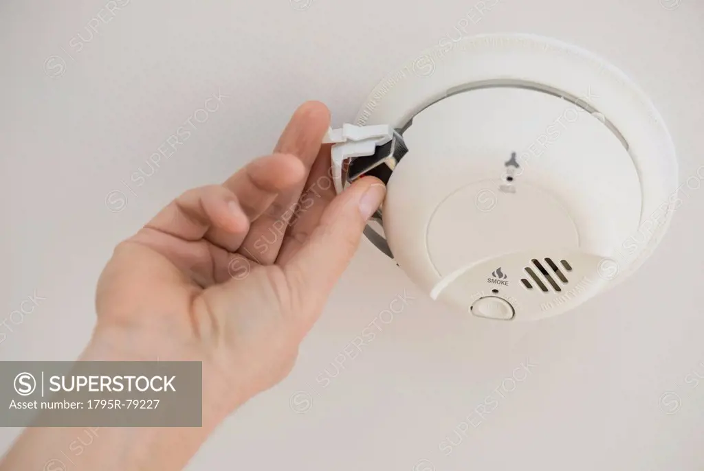 Hand changing battery in smoke alarm
