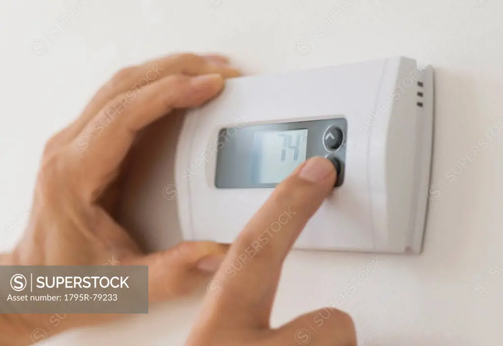 Hand changing settings on air conditioning thermostat