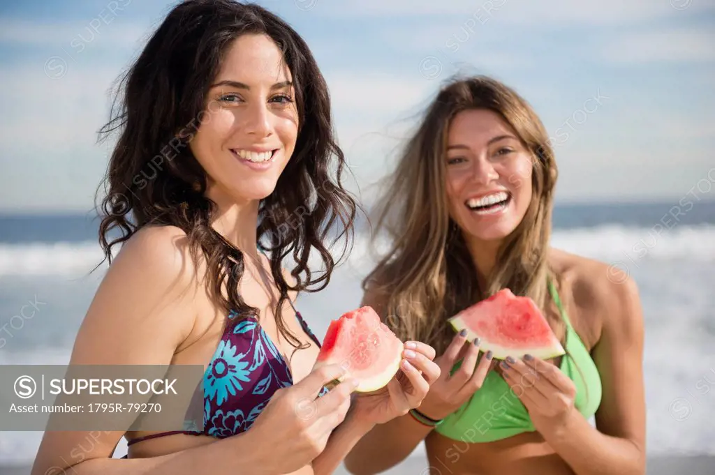 Two women eating watermelon at beach