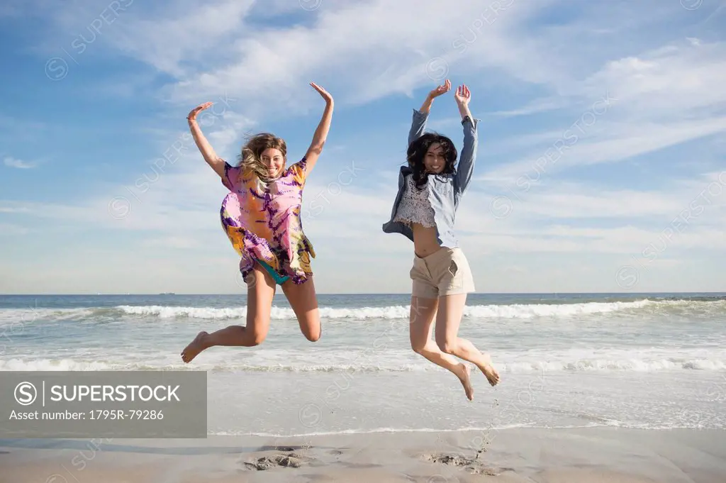 Two young women jumping on beach