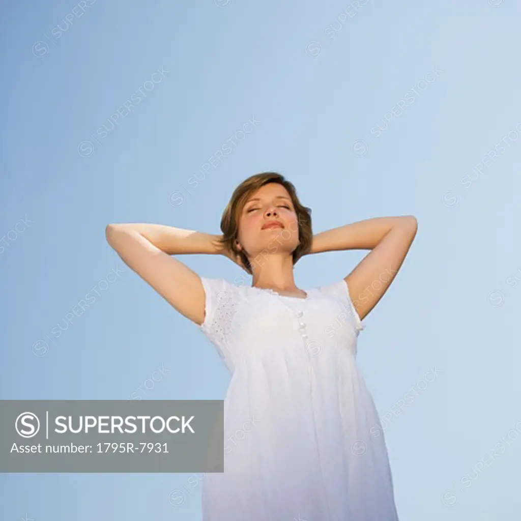 Low angle view of woman with arms behind head