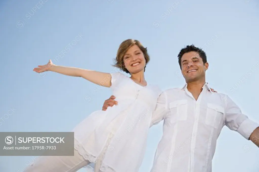 Low angle view of couple with arms outstretched