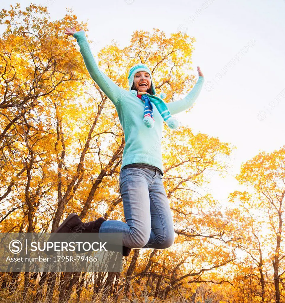 Happy young woman jumping in autumn forest