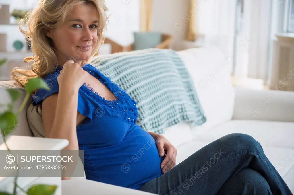 Portrait of pregnant woman sitting on sofa