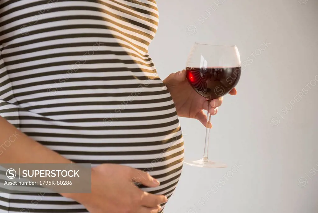 Pregnant woman holding glass of red wine
