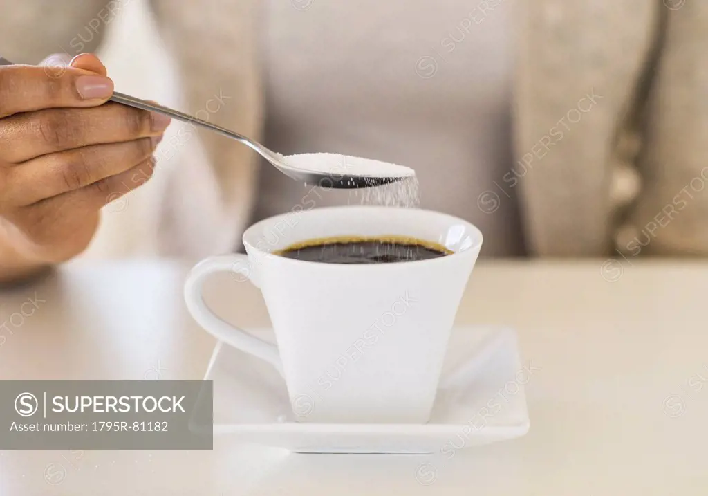 Close-up of woman sweetening coffee