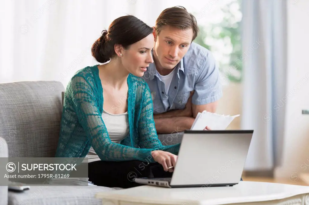 Couple using laptop together to pay bills
