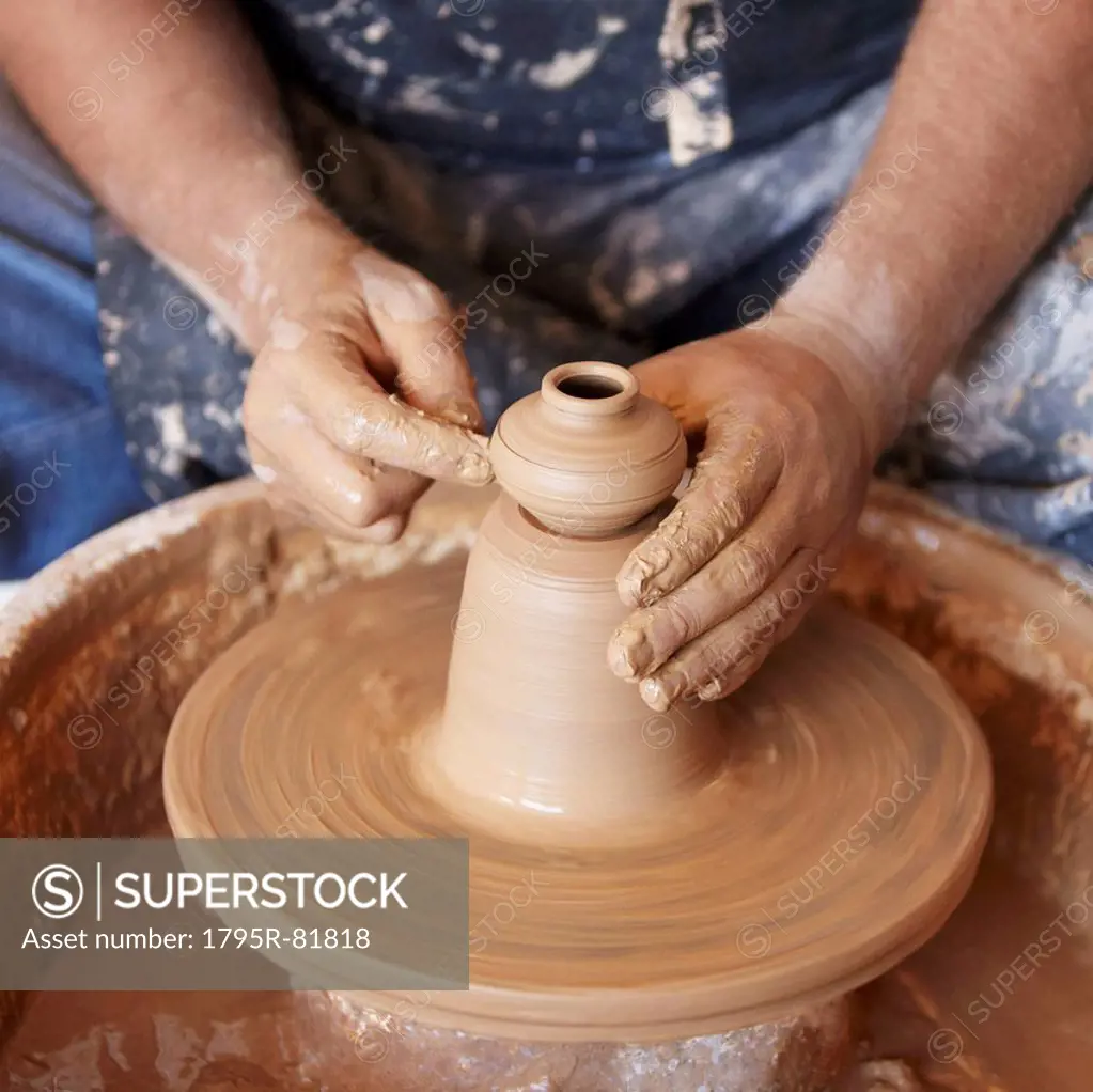 Elevated view of hands working with clay on potter's wheel