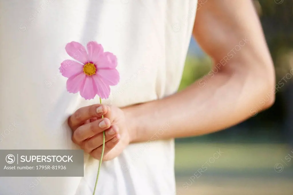 Man holding flower behind back