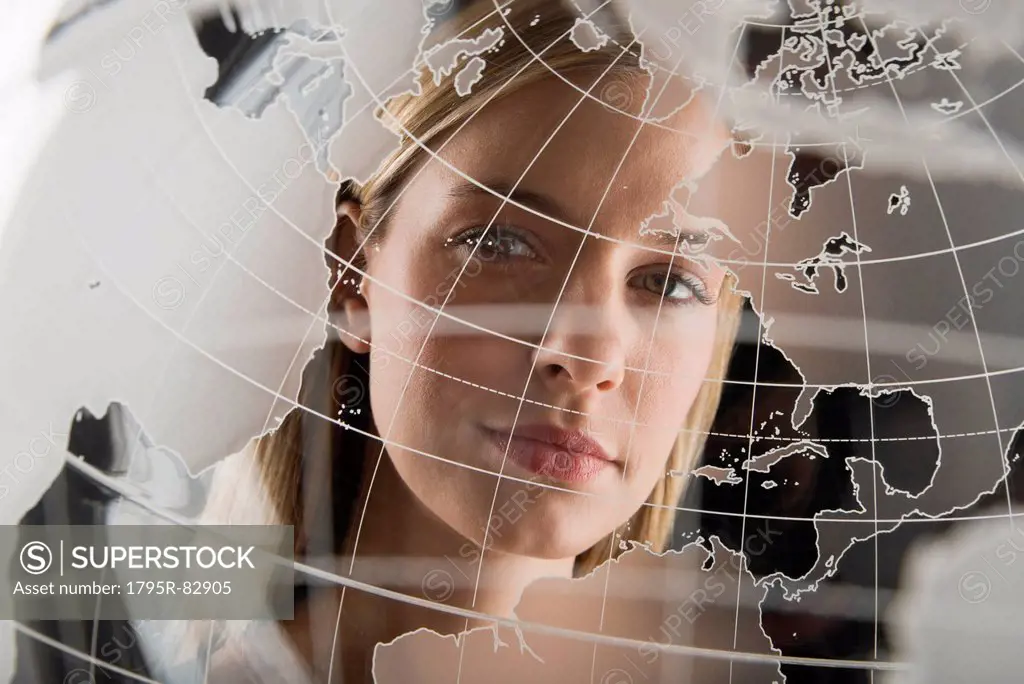 Studio portrait of woman peering through translucent world map