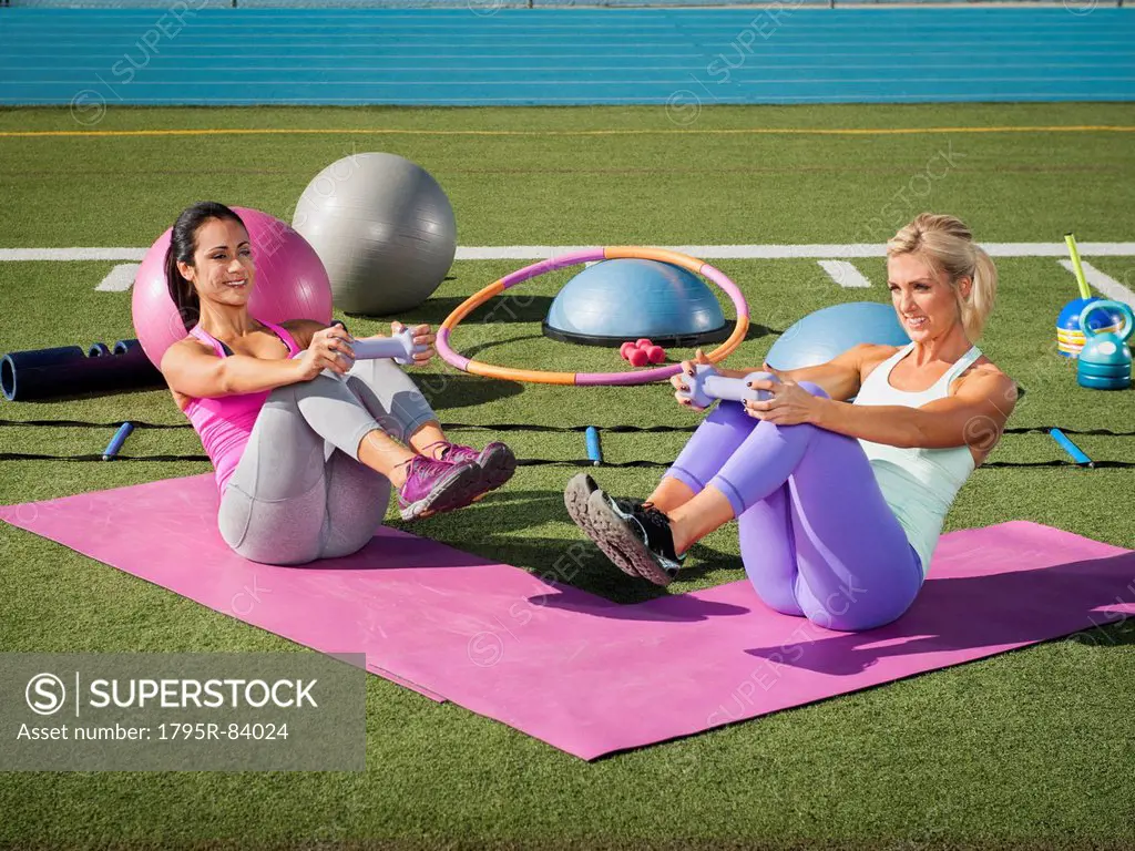 Two women exercising at sports field