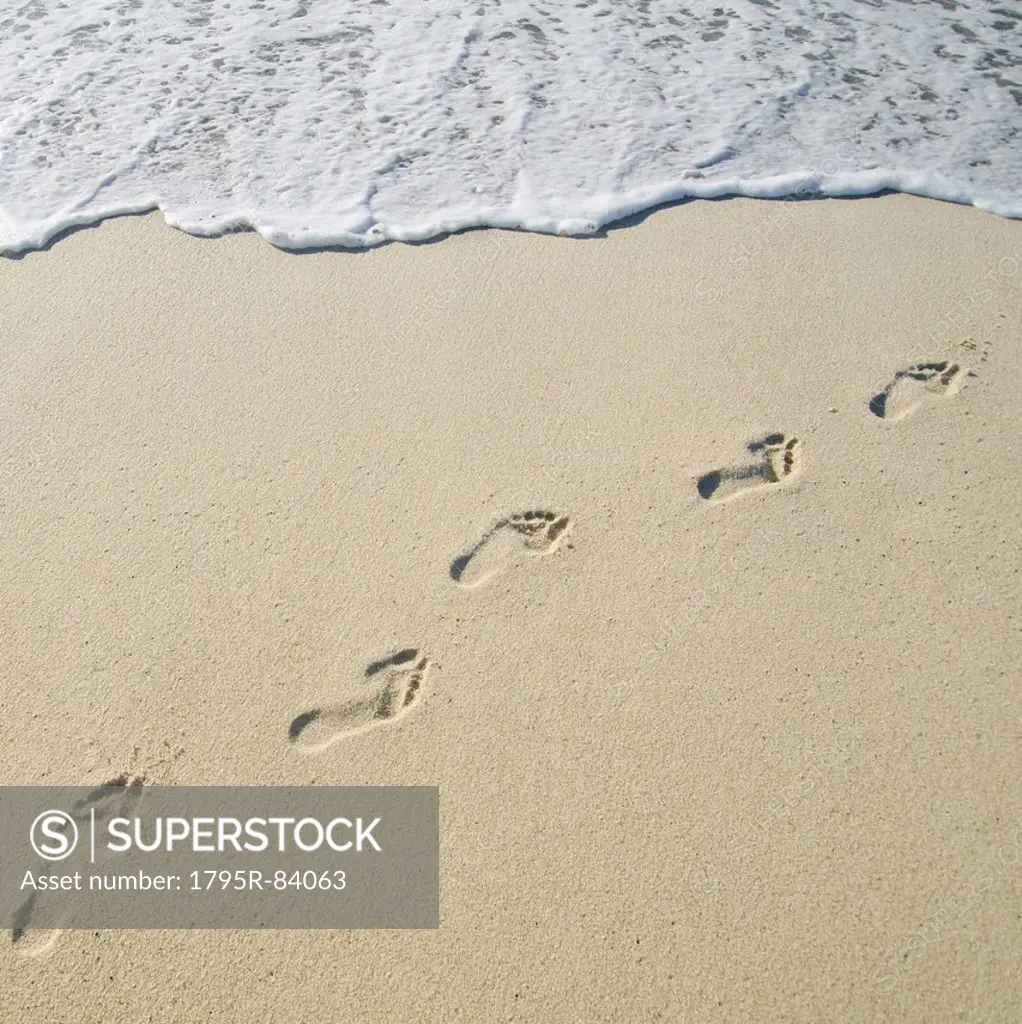 Footprints on Sandy Beach leading into sea