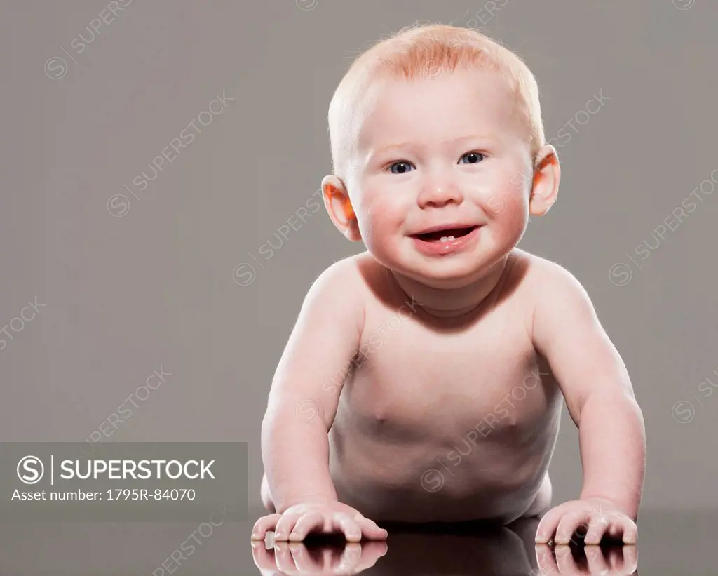 Studio shot of naked baby boy (18-23 months) crawling