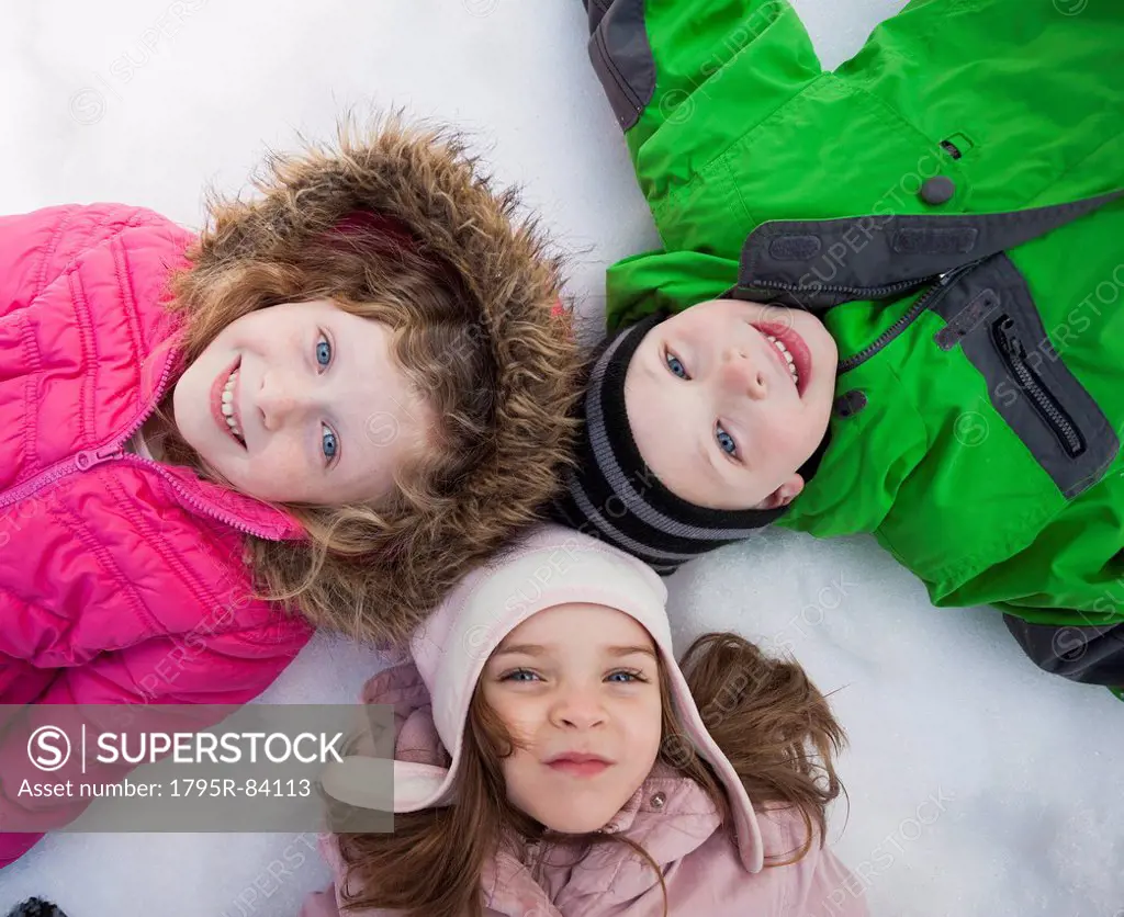 Directly above portrait of three children (2-3, 4-5) lying on snow