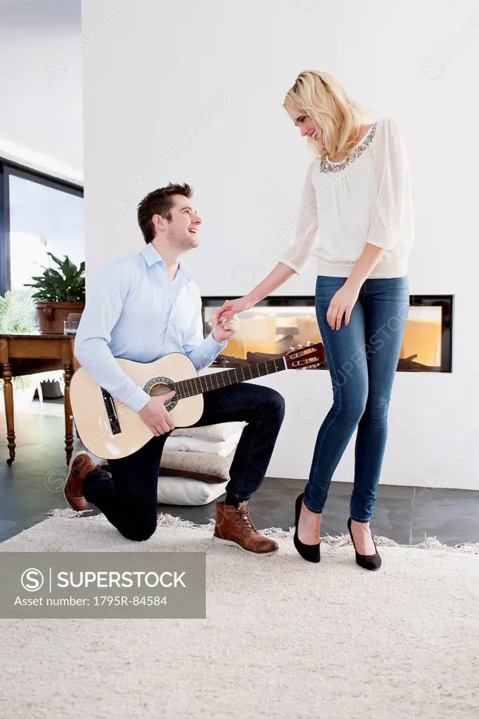 Man playing guitar in front of woman