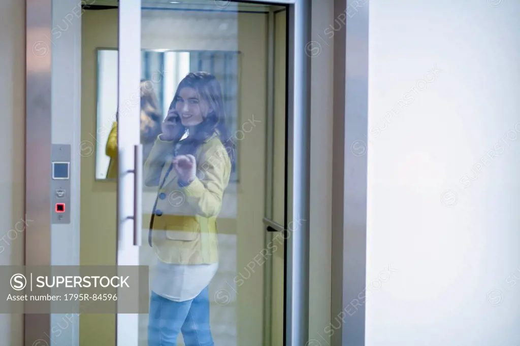 Woman opening glass door and talking on cell phone