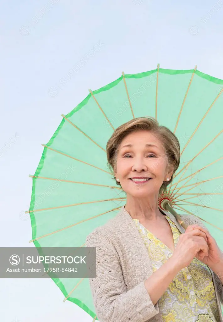 Portrait of senior woman holding green parasol