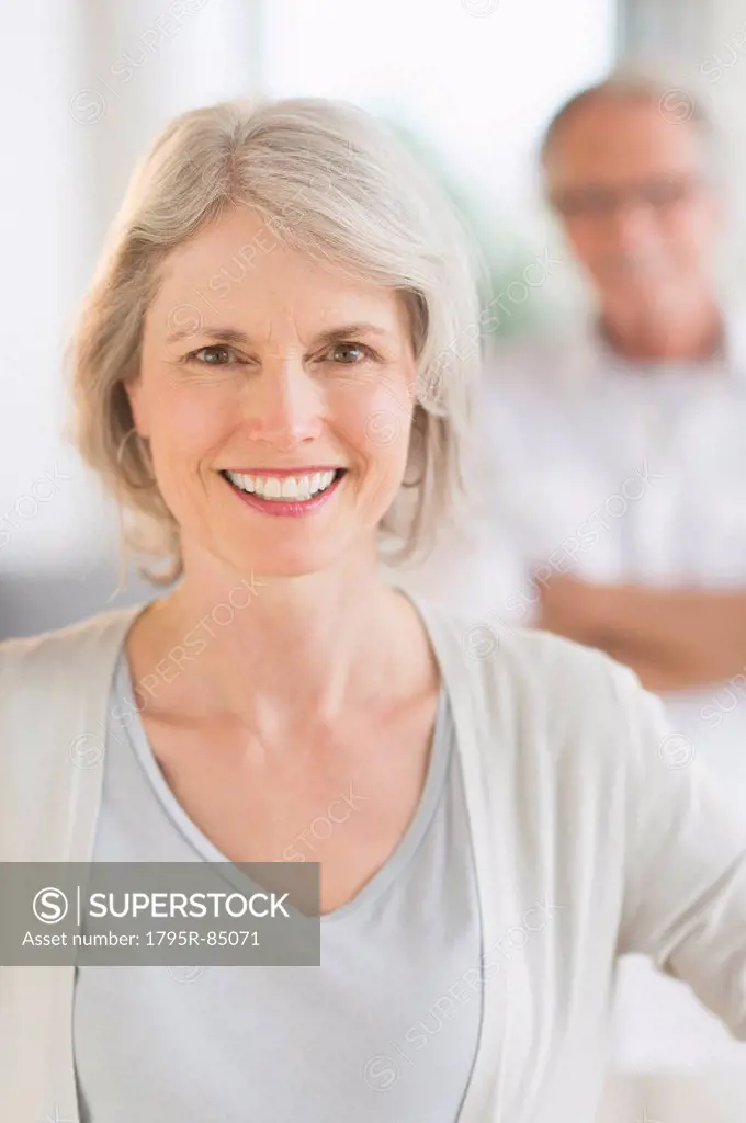 Portrait of senior woman, man in background