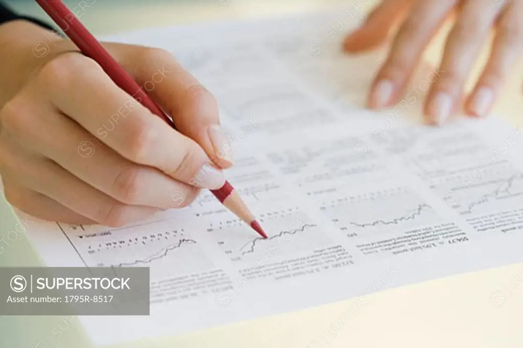 Woman writing on financial charts
