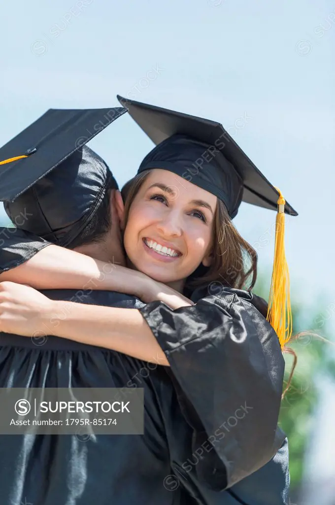 Female and male student embracing on graduation ceremony