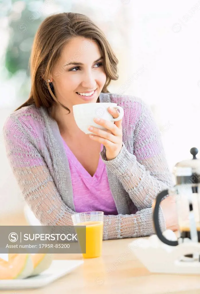Young woman drinking tea at table