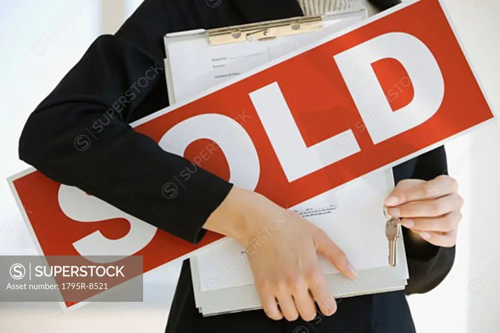 Real Estate agent holding clipboard and Sold sign