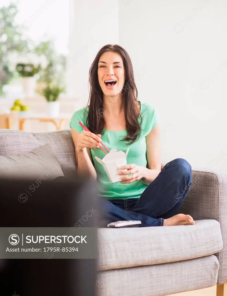 Portrait of woman watching tv and eating take out food