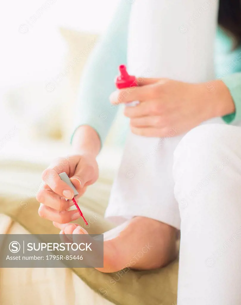 Woman sitting on bed and polishing toe nails