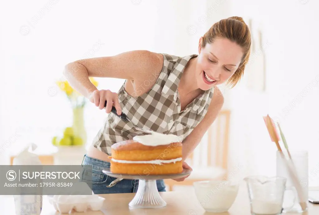 Woman decorating cake in kitchen