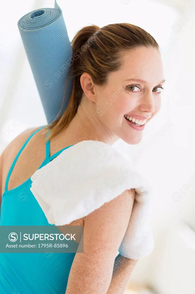 Woman carrying exercise mat and towel