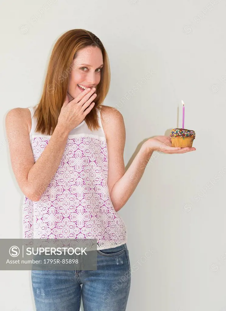Studio portrait of woman holding birthday cupcake