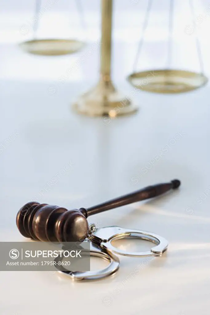 Gavel on handcuffs with scales in background