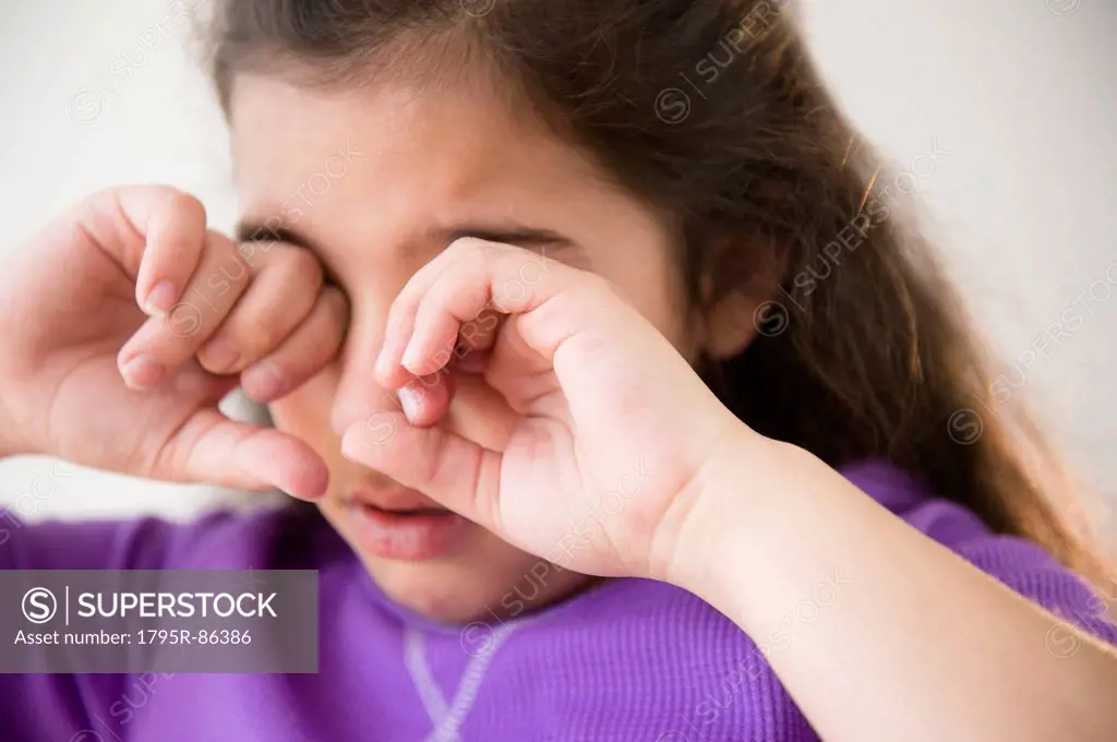 Girl (8-9) crying and covering eyes