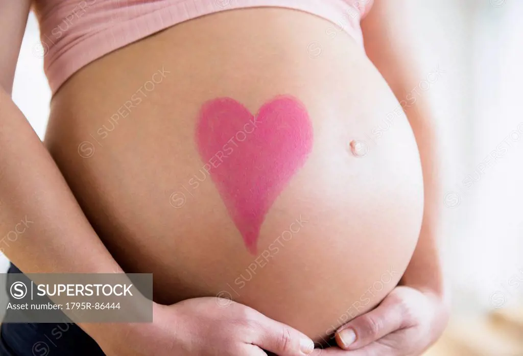 Mid section of pregnant woman with drawing of heart on belly
