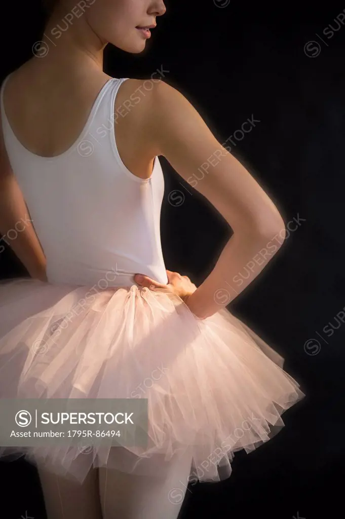 Teenage (16-17) ballerina with hand on hip wearing tutu