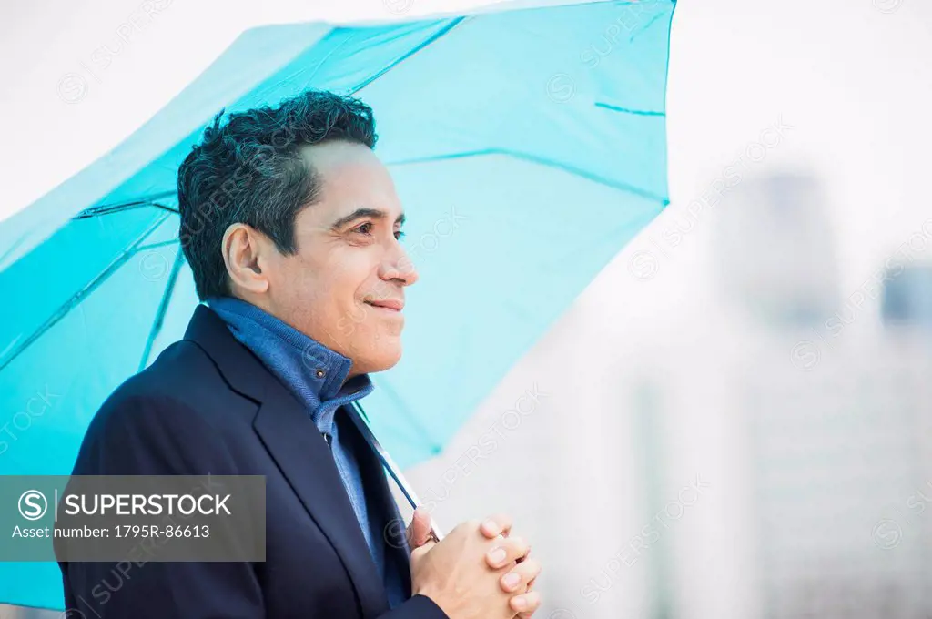 Portrait of man holding blue umbrella