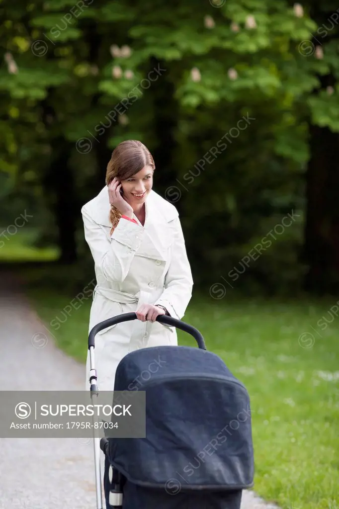 Mother with pram in park talking on mobile phone