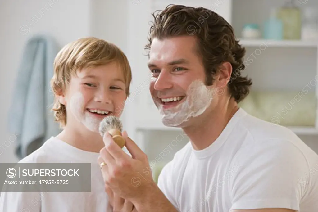 Father putting shaving cream on son's face