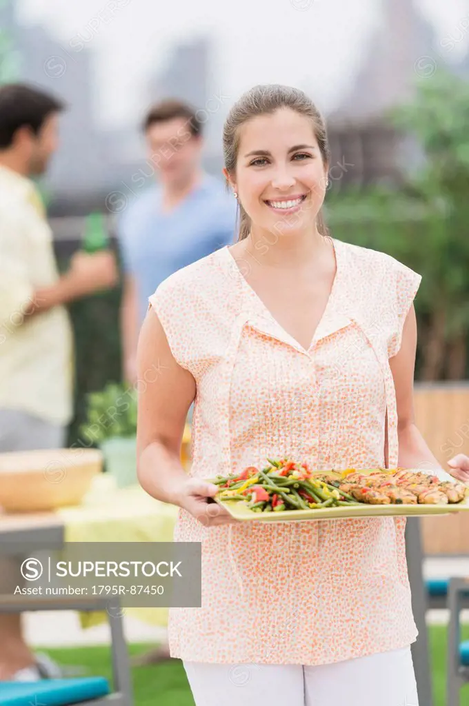 Woman carrying tray with food in garden