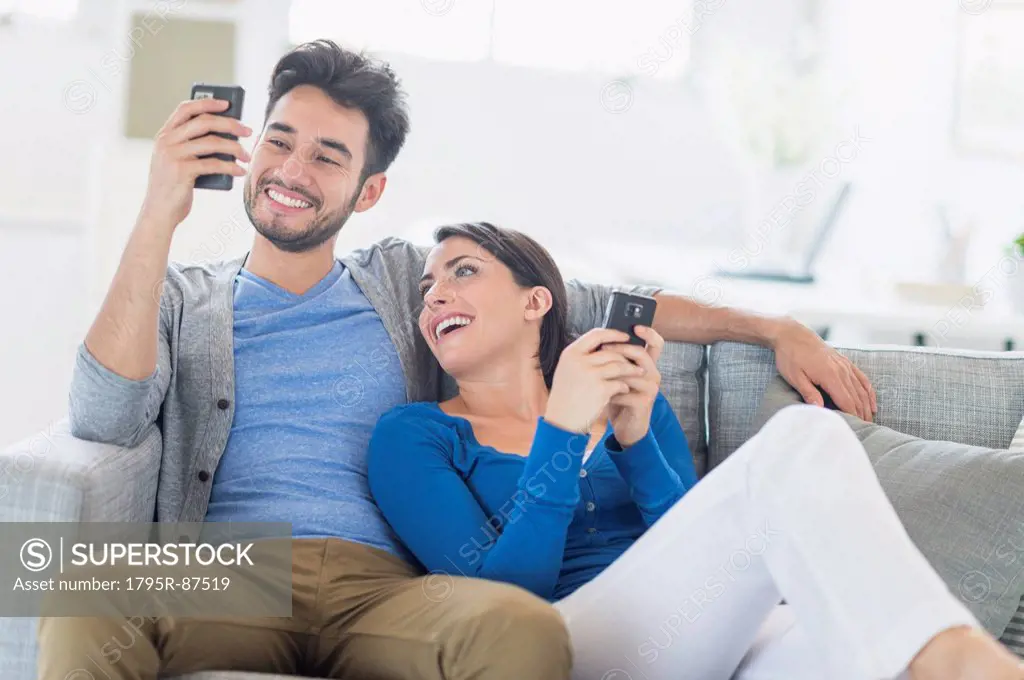 Couple relaxing on sofa with cell phones