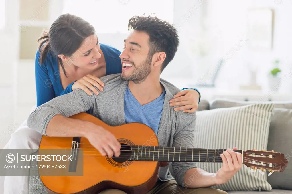 Man playing guitar while woman embracing him