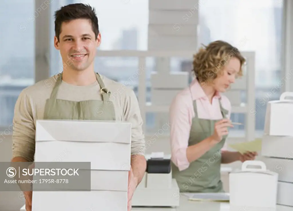 Male bakery worker carrying stack of boxes