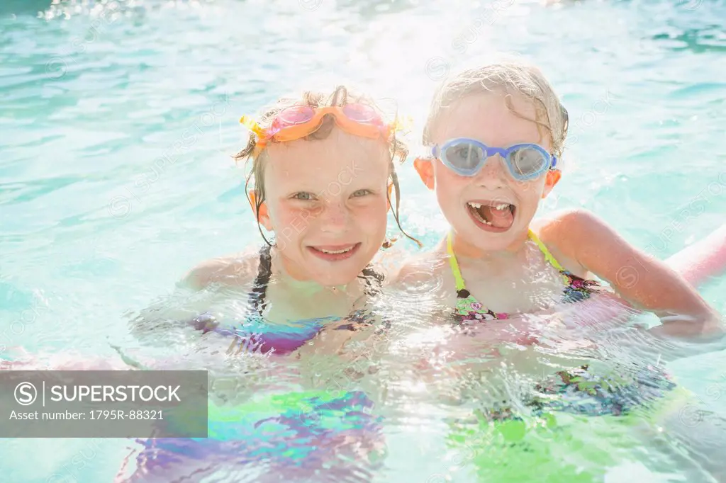 Girlfriends (4-5, 8-9) playing in swimming pool