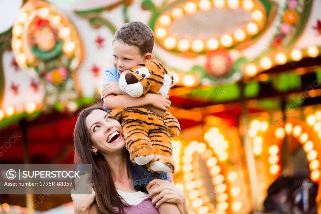 Mother giving her son (4-5) piggyback ride in amusement park