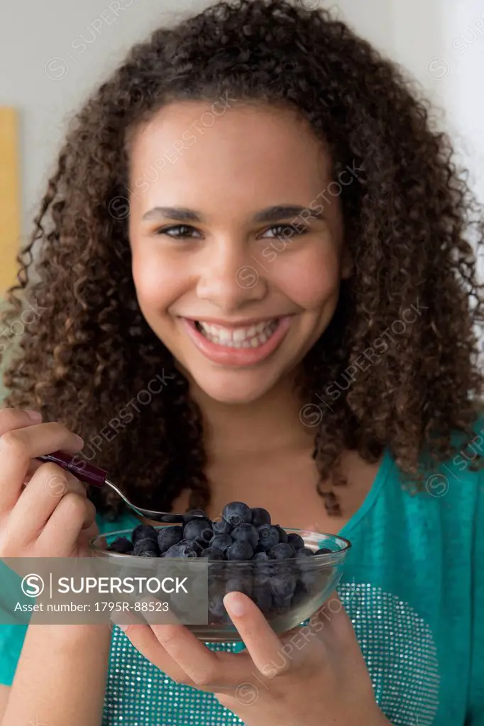 Girl (12-13) holding bowl of black berries