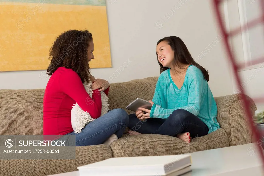 Two friends (12-13,16-17) sitting on sofa