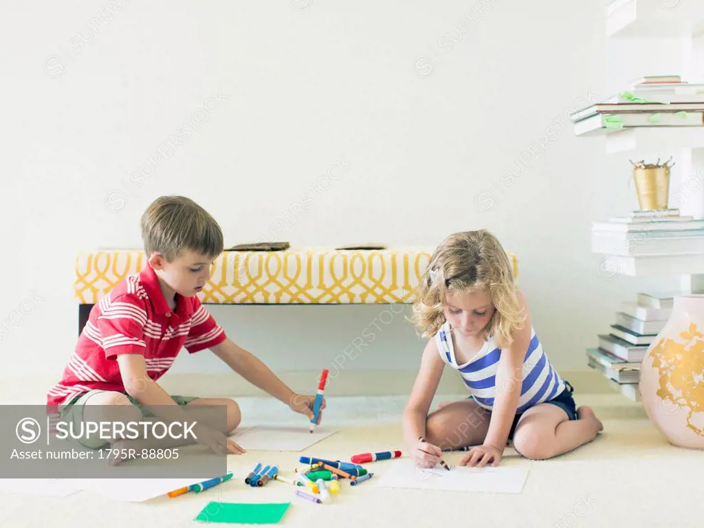 Boy and girl (4-5, 6-7) sitting on floor and drawing