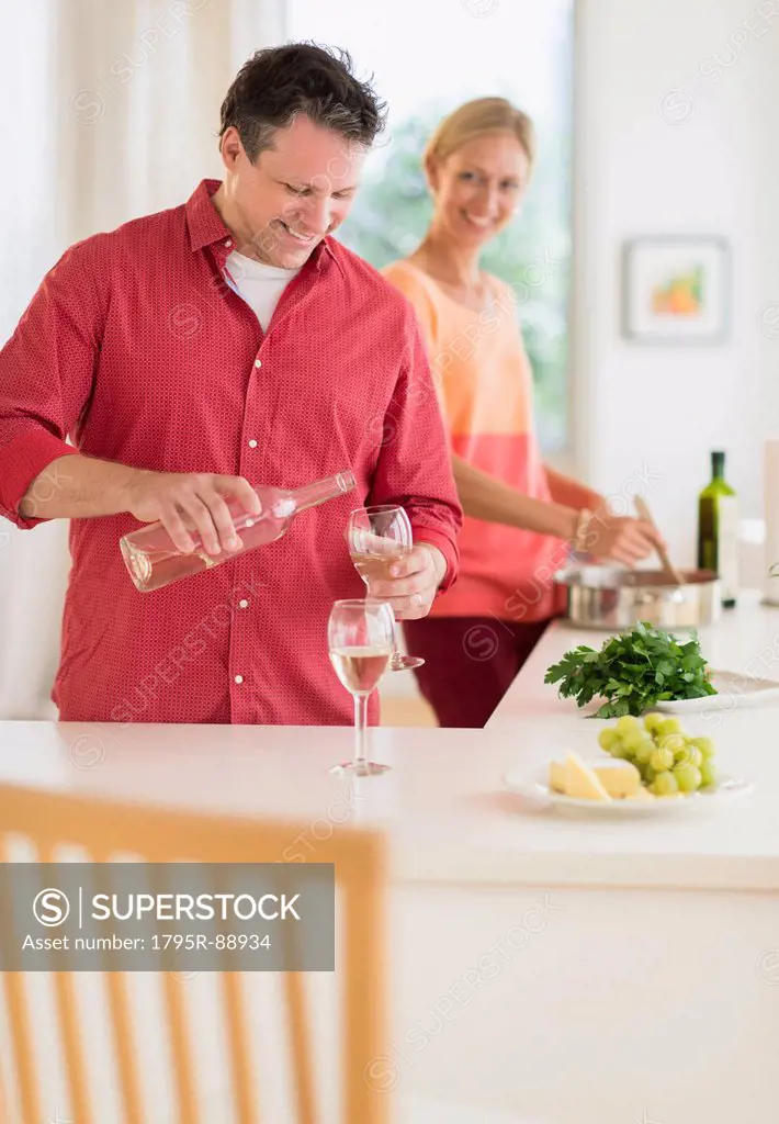 Couple cooking at home, man pouring wine