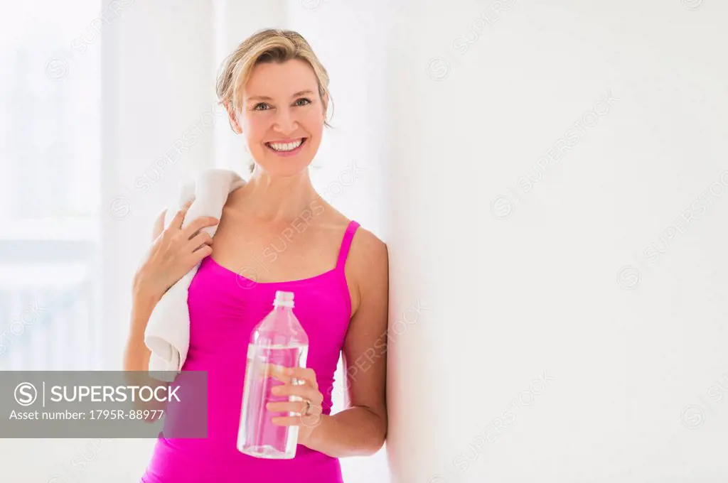 Portrait of woman in sports clothing holding water bottle