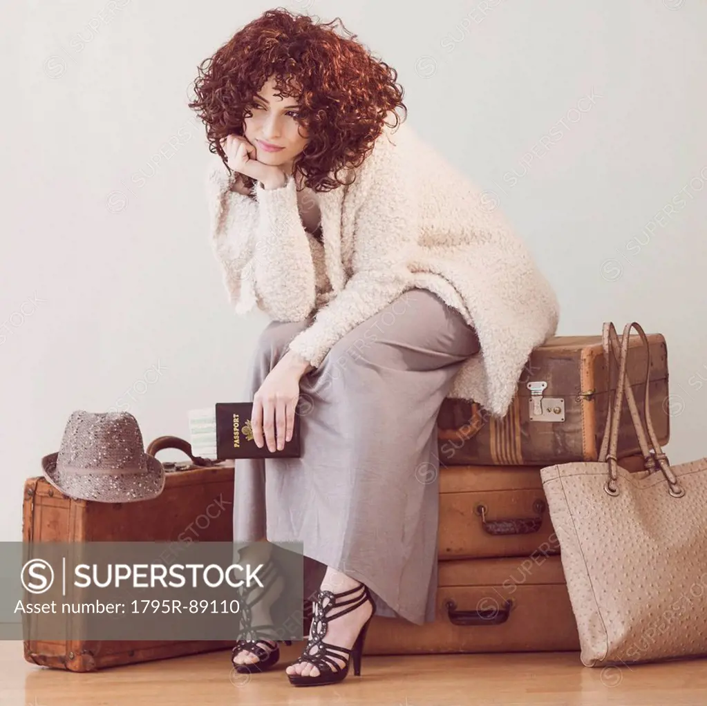 Beautiful brunette woman sitting on suitcases